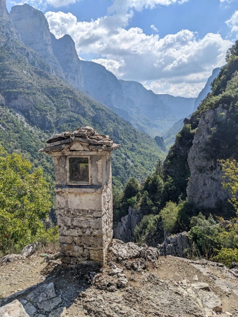 A stone monument in the foreground of the mountain views, Zagori, Greece, Slow Cyclist.