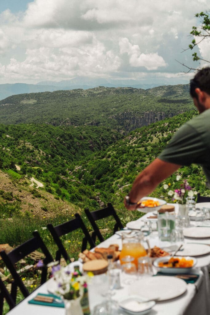 A picnic table with a view over the mountains of Zagori, Greece, set for Slow Cyclists to enjoy a Greek lunch.