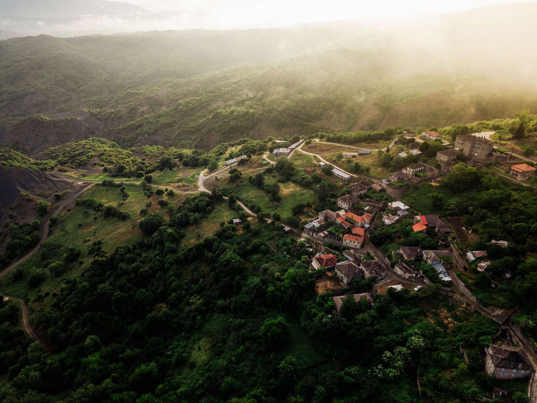 Looking down on stone villages in the mountains of Zagori, shrouded in mist on a Slow Cyclist journey.
