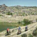 The Slow Cyclists riding alongside a river and rock formations in the Douro region, Portugal.